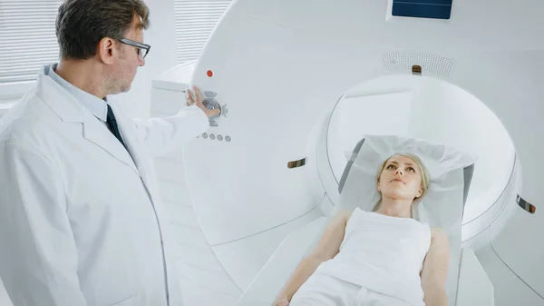 En el laboratorio médico el radiólogo masculino controla la resonancia magnética o la tomografía computarizada o la exploración de la PET con el paciente femenino que se somete a procedimiento. Equipos médicos modernos de alta tecnología. — Foto de Stock