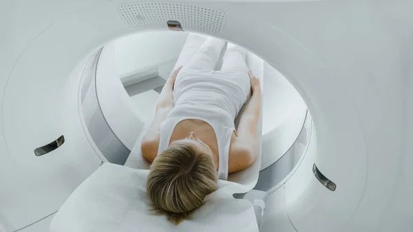 Paciente hembra acostada en una tomografía computarizada o resonancia magnética, la cama se mueve dentro de la máquina escaneando su cuerpo y cerebro. En Laboratorio Médico con Equipo de Alta Tecnología. — Foto de Stock