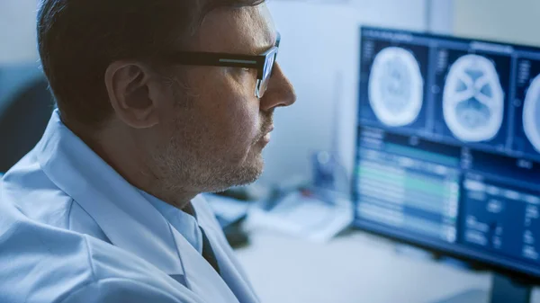 Retrato de perto do médico profissional Olhando para imagens de ressonância magnética ou tomografia computadorizada em seu monitor de computador, procurando sinais de tumor cerebral ou câncer, tentando diagnosticar a doença. — Fotografia de Stock