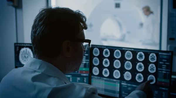 Em Laboratório Médico Paciente é submetido a RM ou TC Processo de digitalização sob supervisão do radiologista, na Sala de Controle Médico Relógios Procedimento e Monitores com Cérebro Scans Resultados. — Fotografia de Stock