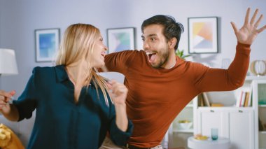 Güzel Mutlu Genç Çift Oturma Odasının Ortasında Dans Ediyor. Erkek Arkadaş ve Kız Arkadaş Evde Dans Ederek Kutlayın.