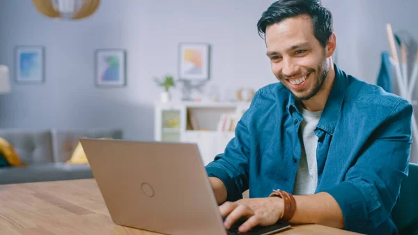 Πορτρέτο του Όμορφου Νέου Χρησιμοποιώντας Laptop Computer στο σπίτι, Παρατηρώντας και χαμογελώντας σε ένα Περιεχόμενο. Άνετο μοντέρνο επίπεδο γίνεται σε σκανδιναβικό στυλ. — Φωτογραφία Αρχείου