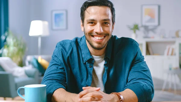 Portrait of Handsome Man Sitting at Desk in His Living Room and Charmingly Smiling. Medium Shot. — Stock Photo, Image