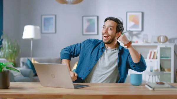 Handsome Happy Man Does Funny Dance Routine while Sitting at His Desk in the Living Room.