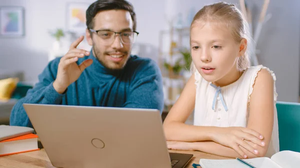 Bright Young Girl Studies met Kind getalenteerde leraar thuis, Ze doen huiswerk. Leraar vreemde talen geeft bijles aan slim klein meisje. Ze gebruiken Laptop en schrijven in het lesboek. — Stockfoto