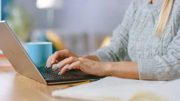 Detailní záběr na ženu s krásnými nehty psaní na notebook, zatímco sedí u svého stolu doma. — Stock fotografie