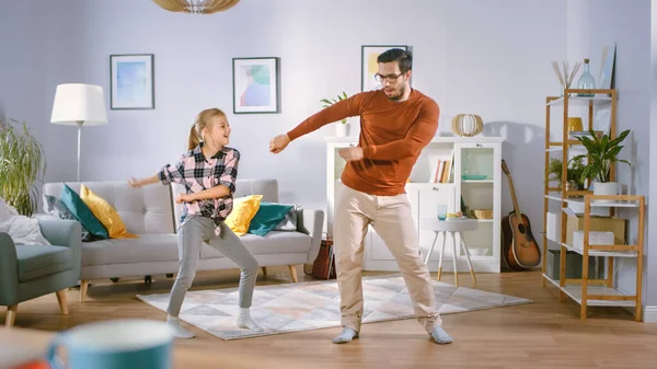 Happy Little Girl dança com o jovem pai no meio da sala de estar. Feliz Tempo em Família, Pai e Filha Dançando em Casa. — Fotografia de Stock