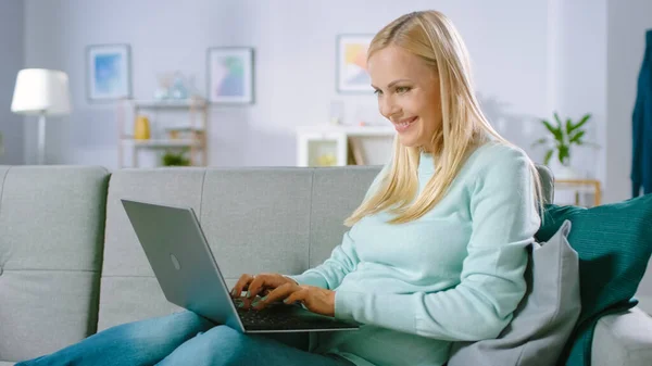 Happy Pregnant Woman Descansando en un Sofá Utiliza Ordenador Portátil. Sonriendo hermoso futuro mamá hace compras por Internet en la computadora. —  Fotos de Stock