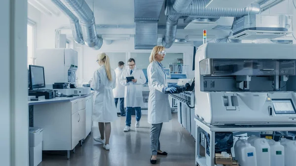 Forskargrupp som arbetar med dator, medicinsk utrustning, analys av blodprover och genetiska material med specialmaskiner i det moderna laboratoriet. — Stockfoto