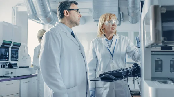 Two Research Scientists Talking about Programming Medical Equipment for Tests. Team of Professionals Doing Pharmaceutical Research in Modern Laboratory — Stock Photo, Image