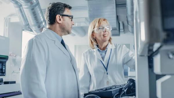 Två forskare talar om programmering medicinsk utrustning för tester. Team of Professionals gör farmaceutisk forskning i moderna laboratoriet — Stockfoto