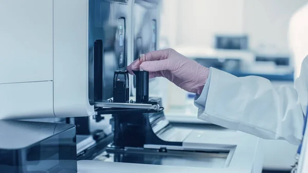 Close-up Female Research Scientists Hand Places Test Tube with Blood Sample Into Medical Analyzing Equipment (dalam bahasa Inggris). Ilmuwan Bekerja di Laboratorium Farmasi Modern — Stok Foto