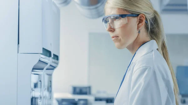 Portrait Shot of Female Research Scientist Standing in Protective Eyeglasses and Working with Medical Analyzing Equipment (en inglés). Científico trabaja en laboratorio farmacéutico moderno. —  Fotos de Stock