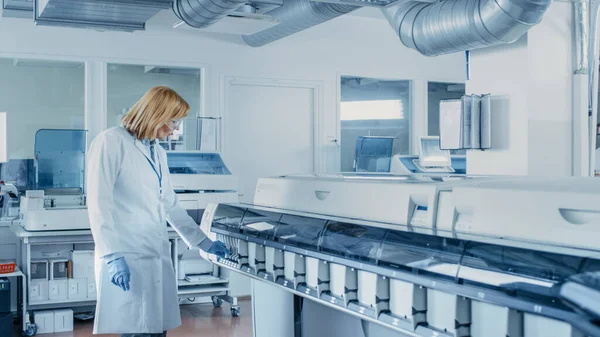 En el laboratorio científica femenina inspecciona equipos médicos que analizan el tubo de ensayo con muestras de sangre. Equipo de trabajo del investigador en laboratorio farmacéutico. —  Fotos de Stock