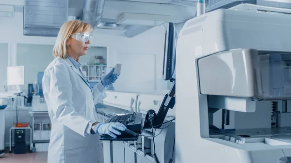 In Laboratory Female Scientist Analyzes Test Tube Data with Blood Samples with Personal Computer (en inglés). Equipo de Investigadores Trabaja en Laboratorio Farmacéutico. —  Fotos de Stock