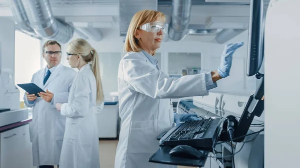Άρρεν και γυναίκες επιστήμονες μιλώντας, χρησιμοποιώντας ψηφιακή ταμπλέτα, Ανώτερος Researchers Προγράμματα Ανάλυση εξοπλισμού. Άνθρωποι που εργάζονται σε Ερευνητικό Πρόγραμμα Γενετικής σε Εργαστήριο Καινοτομίας. — Φωτογραφία Αρχείου