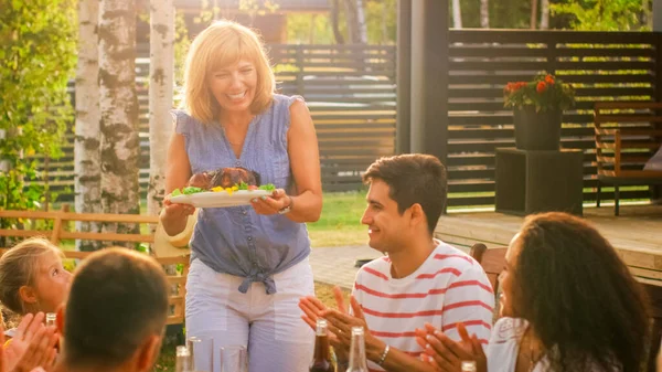 Op het Familie Tuinfeest brengt Moeder Schotel met Geroosterde Vogel naar de Tafel. Familie en vrienden kwamen samen aan de Grote Tafel. Eten, drinken en plezier hebben. — Stockfoto