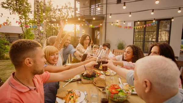 Familie en vrienden verzamelden zich aan de tafel Raise glazen en flessen om een toast en clink glazen te maken. Groot Familie Tuin Feest. — Stockfoto