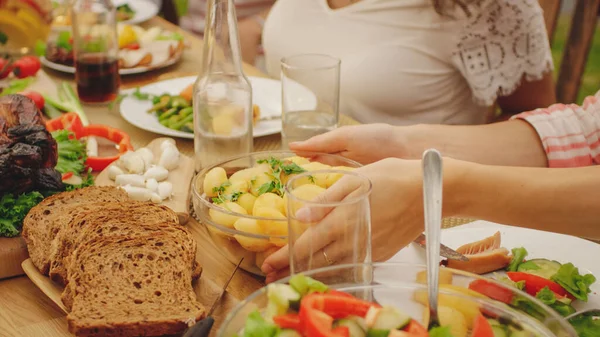 Beim Gartenfest heben Familie und Mädchen einen Teller Kartoffeln auf, um ihn einem Freund zu übergeben. Essen, Trinken und Spaß haben. Fokus auf das Gericht. — Stockfoto