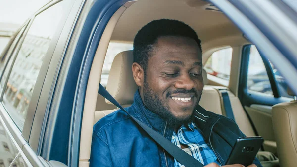 Schöne Unternehmerin, die auf dem Beifahrersitz eines Autos unterwegs ist, benutzt Smartphone und lächelt. Kamerafahrt von außerhalb des Fahrzeugs. — Stockfoto