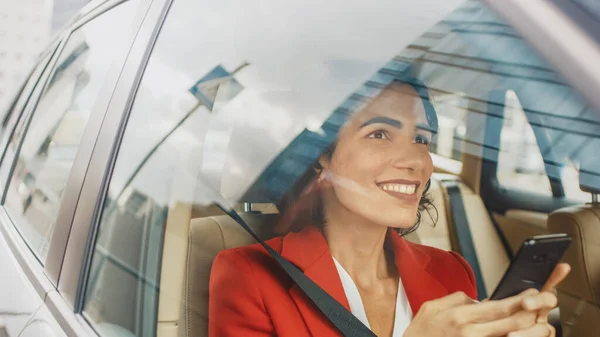 Schöne Frau, die im Auto unterwegs ist, auf dem Beifahrersitz sitzt, Smartphone benutzt, Nachrichten tippt, im Internet surft. Kamerafahrt von außerhalb des Fahrzeugs. — Stockfoto