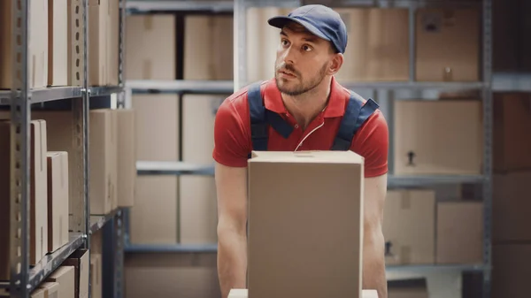 Warehouse Worker 검색 한 Cardboard Boxes 및 Parcels of the Shelf. 그는 상자를 수집하여 카트에 싣는다. — 스톡 사진