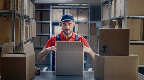 Profesional Warehouse Worker termina la orden, sellando cajas de cartón listas para el envío. En las filas de fondo de estantes con cajas de cartón con pedidos listos. — Foto de Stock