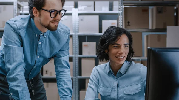 Gerentes de inventario de almacenes masculinos y femeninos hablando, resolviendo problemas, usando computadoras personales y chequeando existencias. En las filas de fondo de estantes llenos de paquetes de cajas de cartón. — Foto de Stock