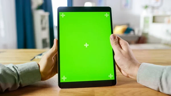 First Person Shot of a Man Using Hand Gestures on Green Mock-up Screen Digital Tablet Computer in Portrait Mode miközben ül az asztalánál. A háttérben Hangulatos nappali. — Stock Fotó