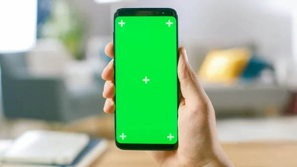 Közelkép egy Mans Hand Holding Green Mock Screen Smartphone-ról. Modern mobiltelefon. A háttérben Hangulatos nappali vagy Home Office. — Stock Fotó