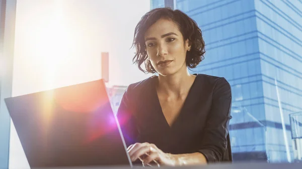 Low-Angle-Porträt der schönen erfolgreichen weiblichen Führungskraft, die in ihrem modernen, sonnigen Büro an einem Laptop arbeitet. Starke weibliche Führungskraft. — Stockfoto