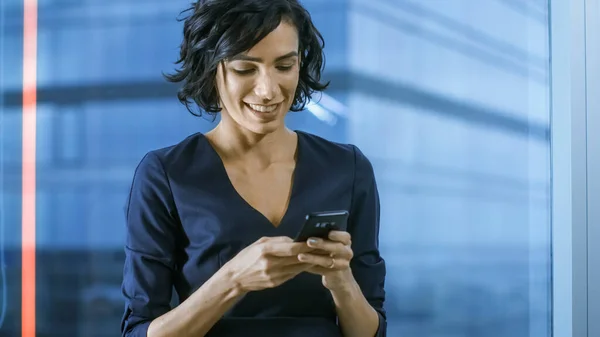 Close-up of the Beautiful Hispanic Woman Using Smartphone. Business Lady in Formal Wear Dress Typing Messages on Mobile Phone. In the Background Window with Cityscape. — Stock Photo, Image