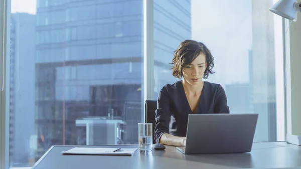 Mulher de negócios bem sucedida bonita que trabalha em um portátil em seu escritório com janela da vista da paisagem urbana. Strong Independend CEO Feminino Dirige Empresa de Negócios. — Fotografia de Stock