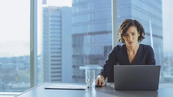 Mulher de negócios de sucesso bonita trabalhando em um laptop e mouse em seu escritório com janela de vista cityscape. Strong Independend CEO Feminino Dirige Empresa de Negócios. — Fotografia de Stock