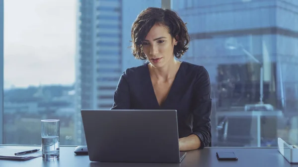 Beautiful Successful Female CEO Works on a Laptop in Her Modern Sunny Office with Cityscape Window View. Forte Líder Empresarial Feminino. — Fotografia de Stock