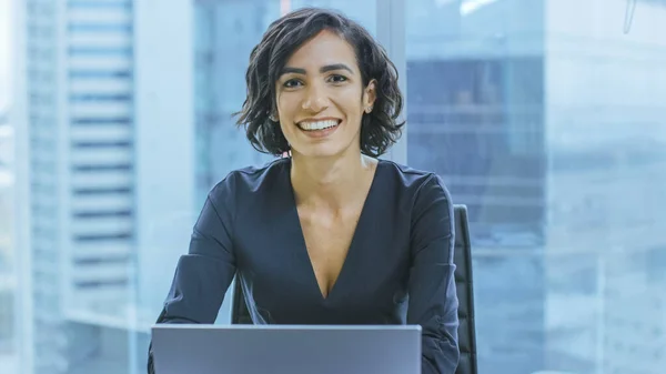 Porträt der erfolgreichen lächelnden Geschäftsfrau, die in ihrem Büro an einem Laptop arbeitet und in die Kamera blickt. Schöne weibliche Independend CEO führt Firma. — Stockfoto