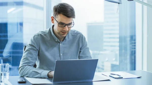 El exitoso joven empresario trabaja en una computadora portátil en su oficina moderna. Joven inteligente trabajando para un nuevo y prometedor Startpup. — Foto de Stock