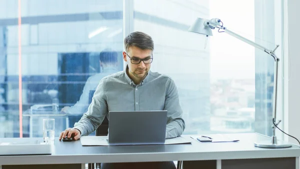 Succès jeune homme d'affaires travaille sur un ordinateur portable dans son bureau moderne. Jeune homme intelligent travaillant pour un nouveau Startpup prometteur. — Photo