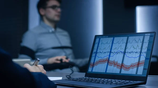 Computer Shows Physiological Measures of a Man Undergoing Lie Detector Polygraph Test. Especialista em Exames Escreve Observações. — Fotografia de Stock