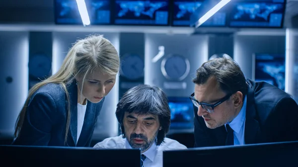 Operadores masculinos y femeninos que trabajan en computadoras en la sala de control del sistema. Analistas de agencias gubernamentales secretas investigando, investigando la seguridad cibernética. —  Fotos de Stock