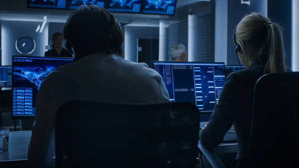 Blick zurück auf die Cyber Security Dispatcher, die am Personal Computer arbeiten und den Datenfluss im System-Kontrollraum voller spezieller Geheimdienstagenten zeigen. — Stockfoto