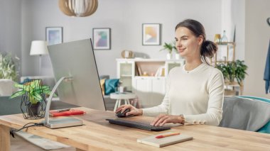 Güzel Genç Kadın 'ın portresi Samimi Oturma odasından kişisel bilgisayarda çalışıyor. Çekici bir şekilde gülümsüyor Kameraya bakıyor.