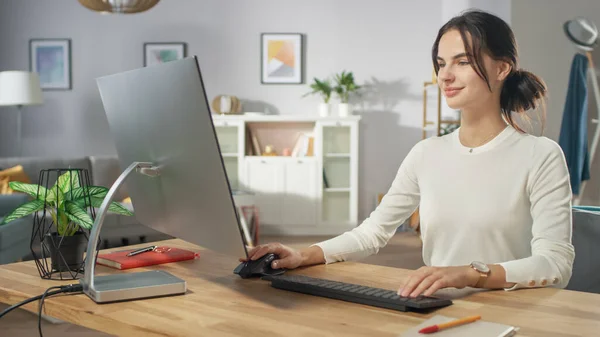 Retrato da bela jovem mulher trabalhando em computador pessoal de sua acolhedora sala de estar. Ela sorri encantadoramente. — Fotografia de Stock