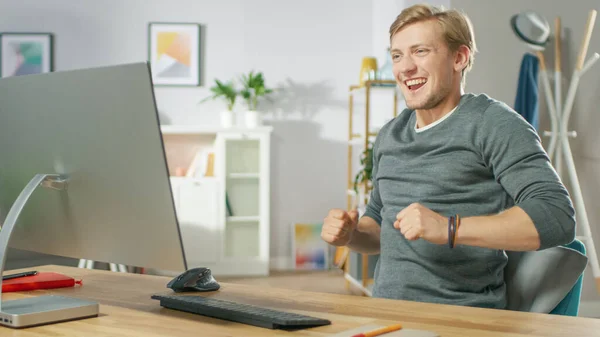 Retrato do Jovem Bonito dança enquanto se senta diante de seu computador. Jovem se divertindo em casa. — Fotografia de Stock