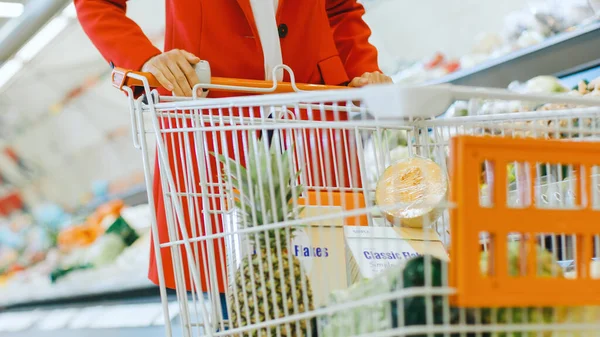 У торговому центрі супермаркету: низькорівневий знімок жінки, що штовхає кошик, наповнений гросмейстером та органічними свіжими овочами . — стокове фото