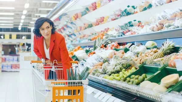 Im Supermarkt: Porträt der schönen lächelnden Frau, die Produkte im Frischebereich auswählt und in den Warenkorb legt. — Stockfoto