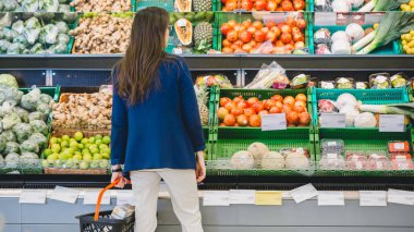 Süpermarkette: Kadın mağazanın Taze Ürün Bölümü 'nden Organik Meyveleri Seçiyor. Cantaloupe 'u arıyor. Alışveriş sepetini tutuyorum. Arka Görünüm Görüntüsü.