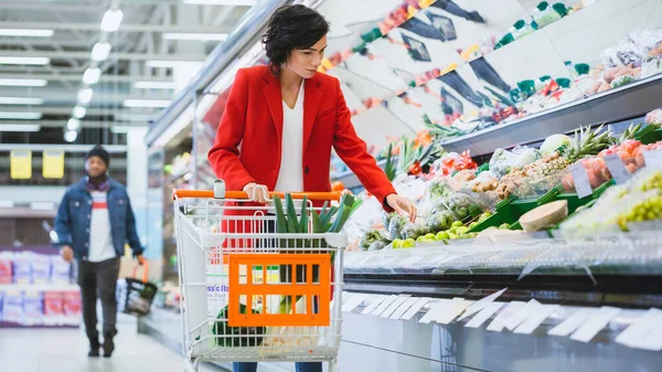 У супермаркеті: красива молода жінка з торговим візком вибирає овочі у секції "Свіже продукування", Пікс Брокколі.. — стокове фото
