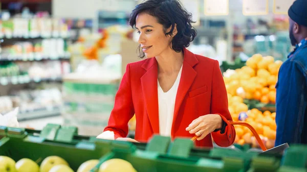 Süpermarkette: "Güzel Gülümseyen Kadın Portresi Taze Ürünler Reyonundan Organik Meyveler Seçiyor ve Onları Alışveriş Sepetine Alıyor". — Stok fotoğraf