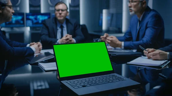 På Table Laptop, som viser Green Mock-up Screen: Team of Policians, Corporate Business Leaders and Lawyers Sitting at the Negotiations Table in the Conference Room, Trying to Come to an Agreement. – stockfoto